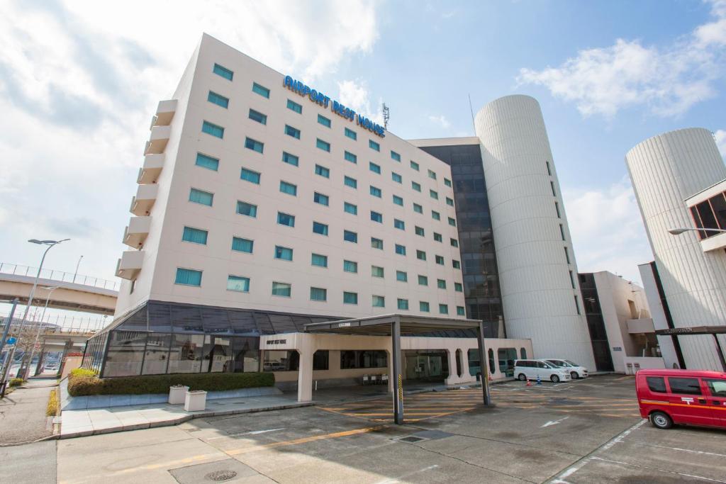 ein großes weißes Gebäude mit einer Bushaltestelle auf einem Parkplatz in der Unterkunft Narita Airport Rest House in Narita