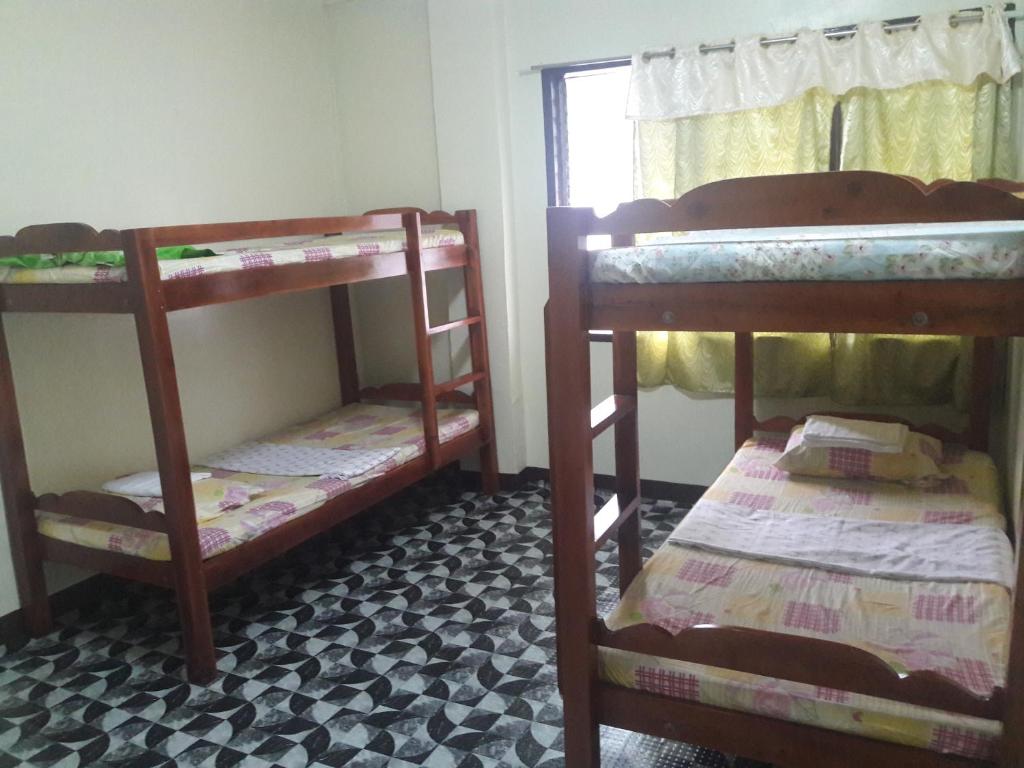 a room with three bunk beds and a window at Villa Travellers House in Moalboal