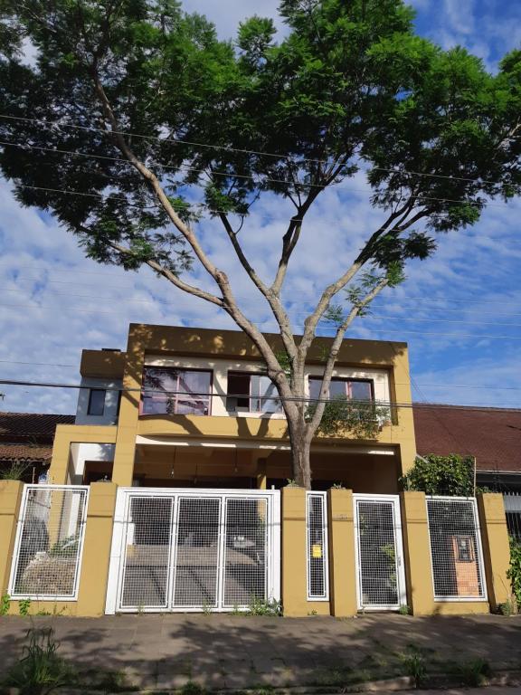Una casa amarilla con un árbol delante. en Hostel Casa Grande, en Porto Alegre