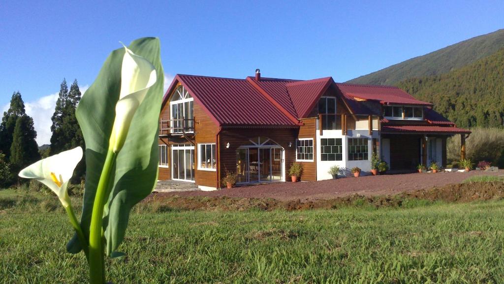 uma casa com um telhado vermelho num campo em L'Arum des Prairies em Bras des Calumets