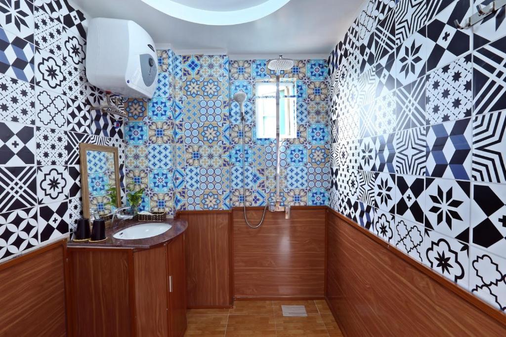 uma casa de banho com paredes em azulejos azuis e brancos e um lavatório. em La Ava’s Home em Hanói