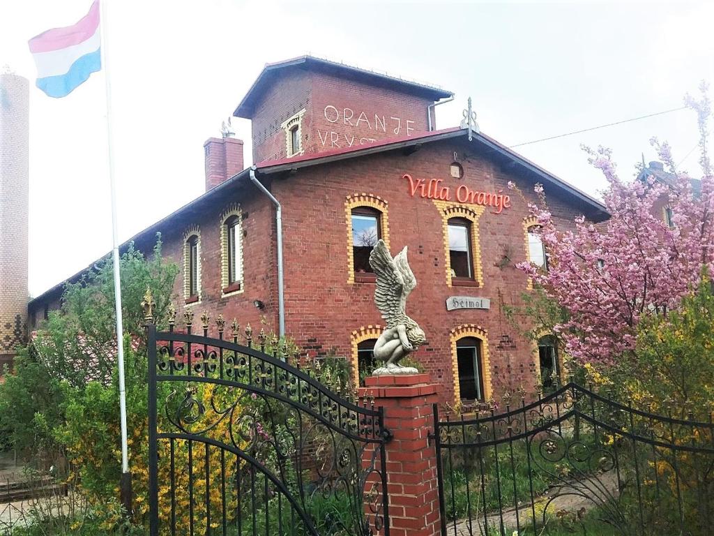 un viejo edificio de ladrillo con una estatua delante de él en Villa Oranje, en Bolków