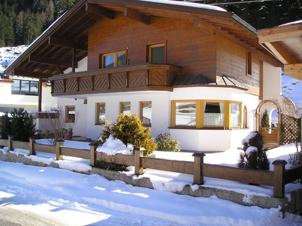 una casa con una valla de madera en la nieve en Apartments Weißstein, en Gries im Sellrain