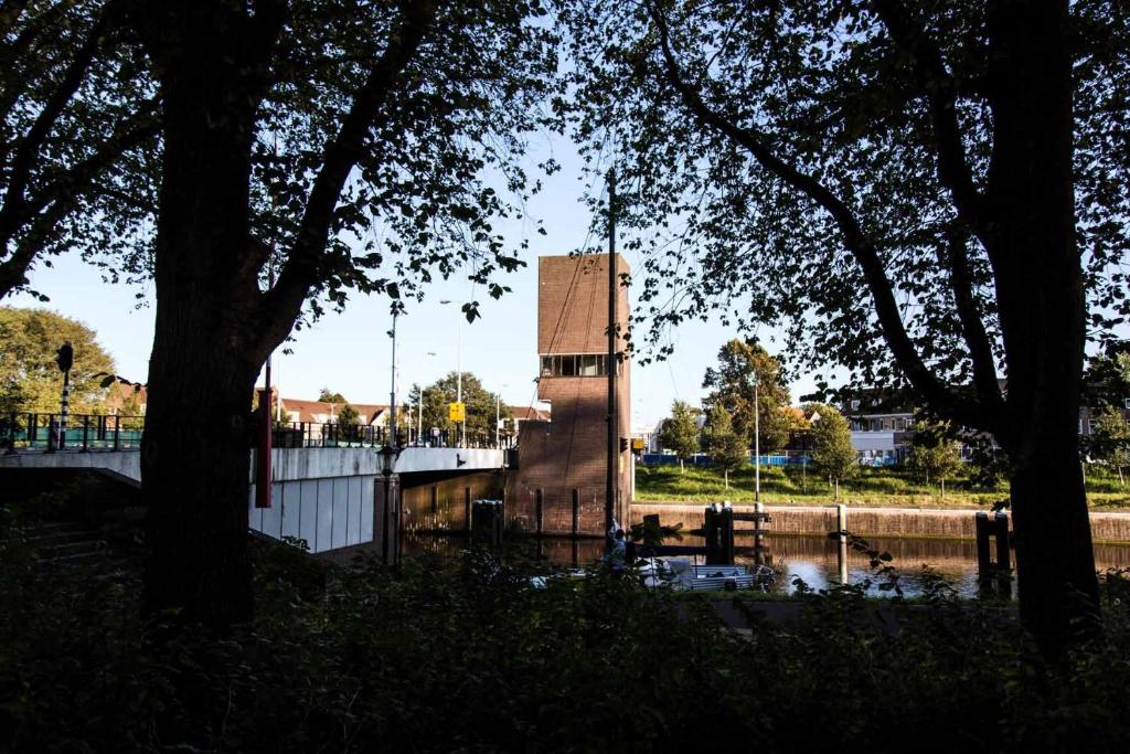 een gebouw midden in een rivier met bomen bij SWEETS - Gerben Wagenaarbrug in Amsterdam