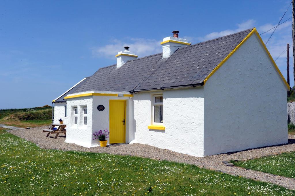 Yellow Cottage, Doolin في Knockfin Cross Roads: كوخ ابيض صغير بباب اصفر