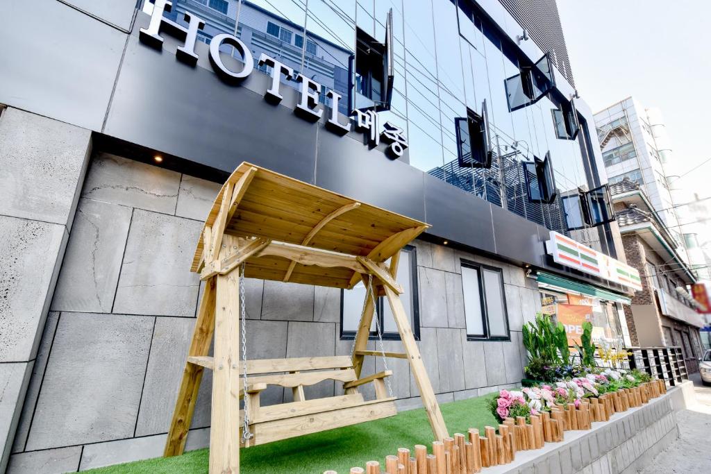 een houten stoel voor een gebouw bij Hotel Maison in Busan
