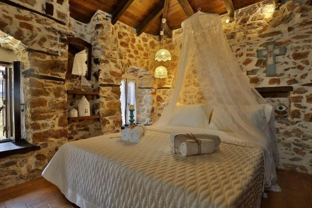 a bedroom with a white bed in a stone wall at Agkaze in Palaios Panteleimonas