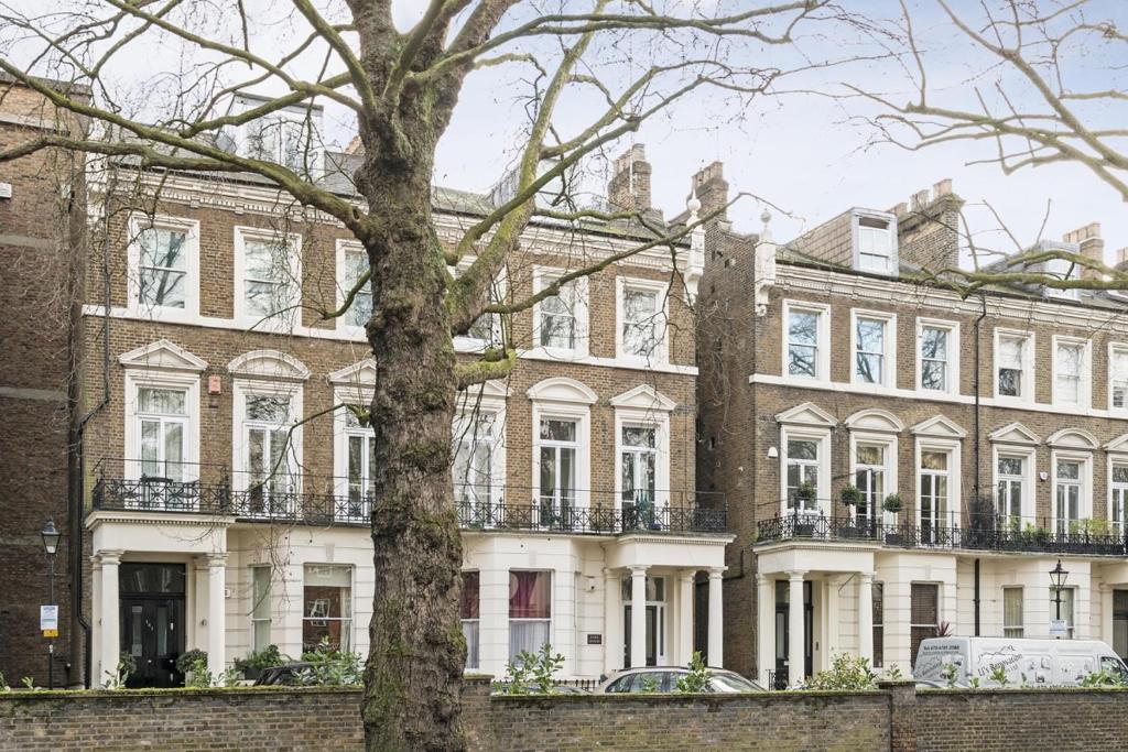 una casa grande con un árbol delante en Holland Park Apartment, en Londres