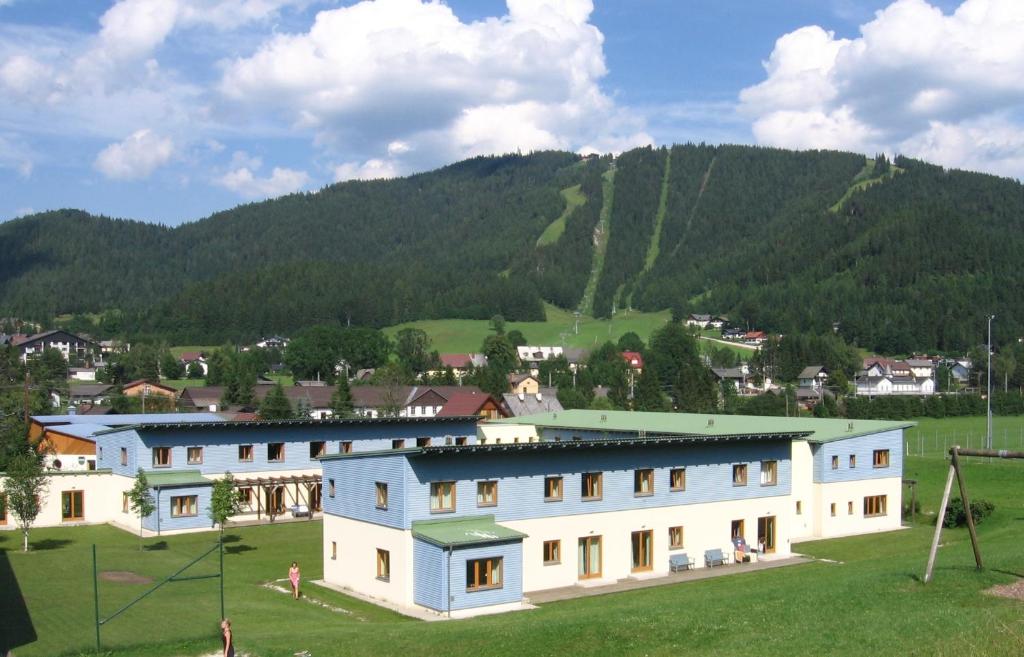 a building in a field with a mountain in the background at JUFA Hotel Erlaufsee in Mariazell