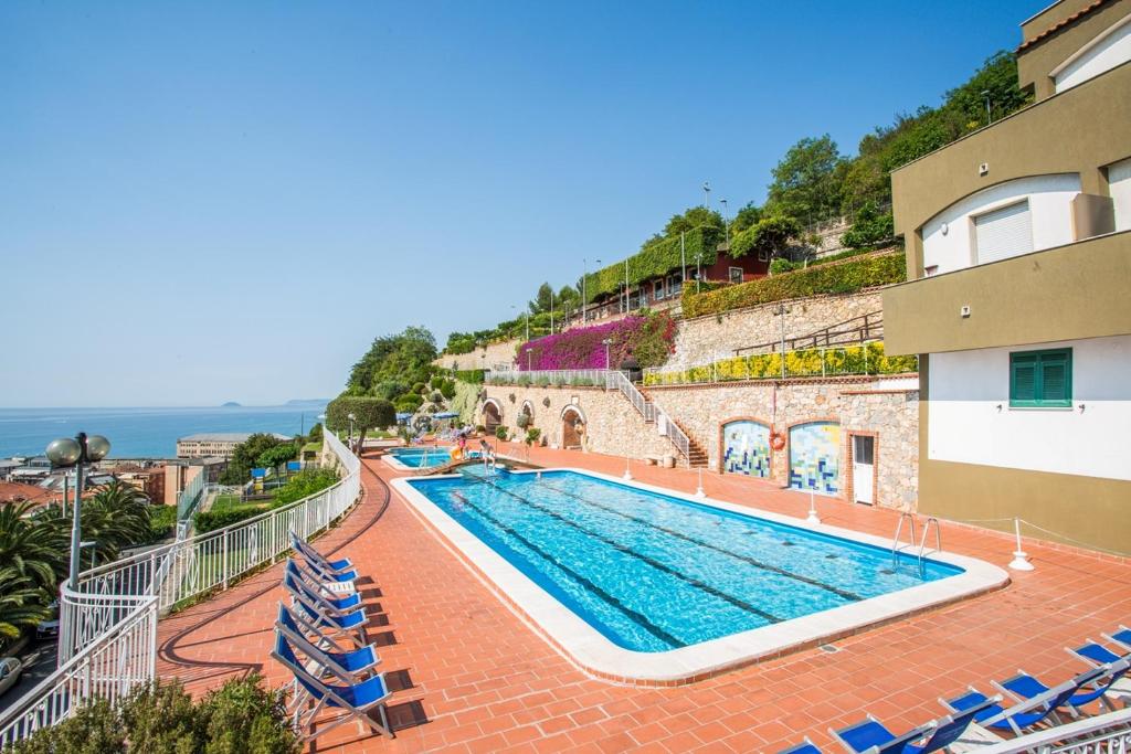 a swimming pool with chairs and the ocean in the background at Residence Sant'Anna in Pietra Ligure