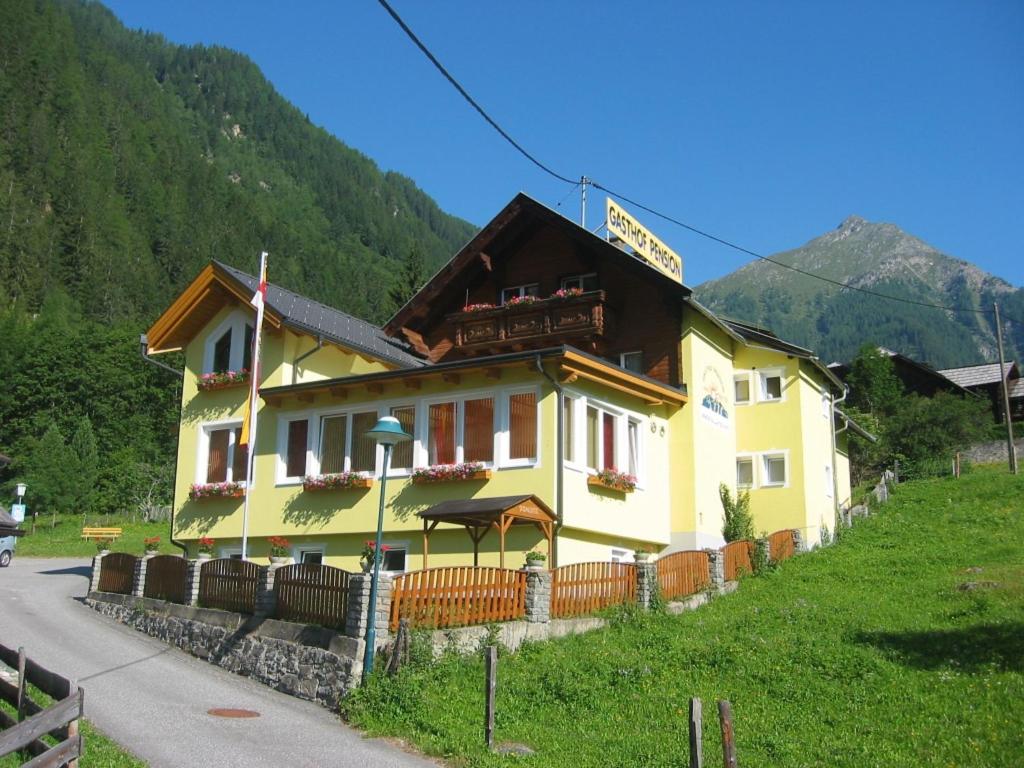 un edificio amarillo en el lateral de una montaña en Gasthof Innerfraganterwirt, en Flattach