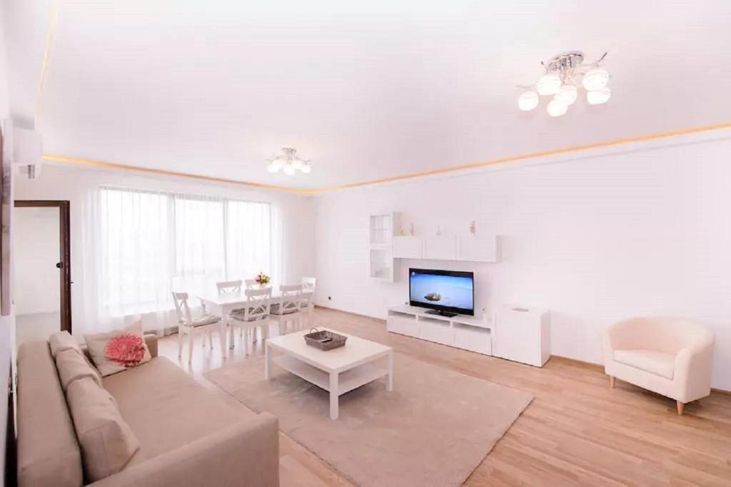 a white living room with a couch and a tv at Isaran 3P Apartment Brașov in Braşov