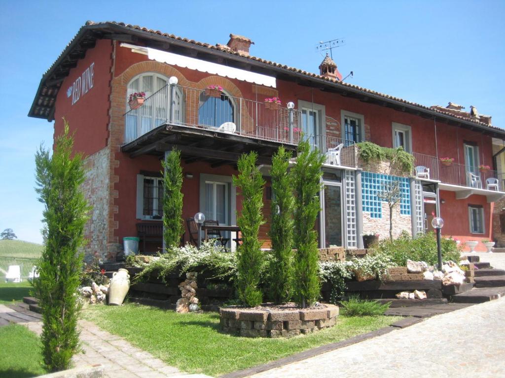 une maison en briques rouges avec des arbres devant elle dans l'établissement Red Wine Camere, à La Morra