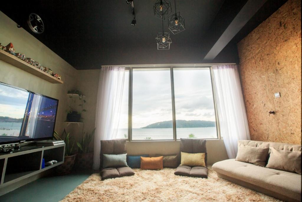 a living room with a couch and a large window at Homy Seafront Hostel in Kota Kinabalu