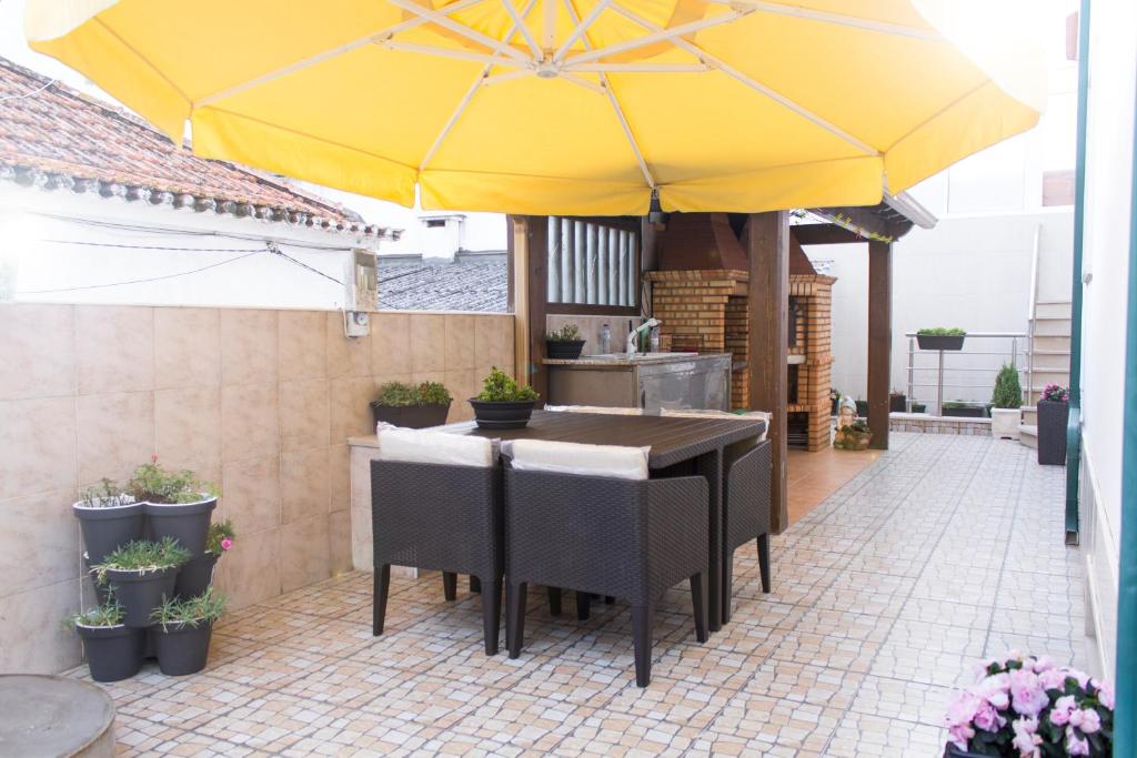 un tavolo e sedie sotto un ombrellone giallo su un patio di Moradia da Ilda - Casas de Férias Nazaré a Nazaré