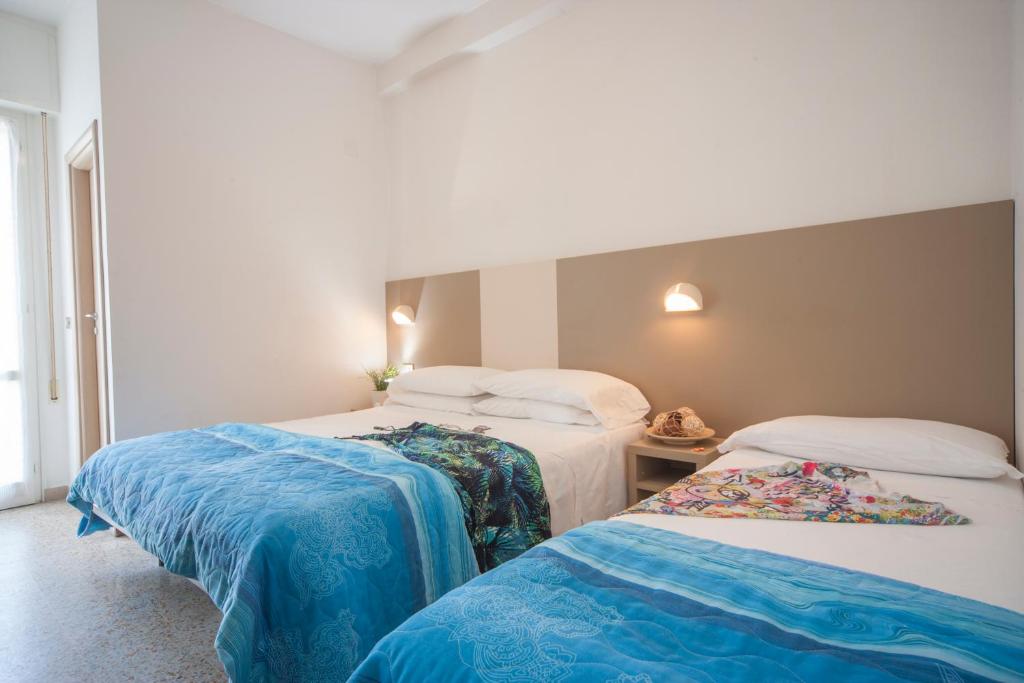 een hotelkamer met 2 bedden met blauwe lakens bij Hotel Bologna in Misano Adriatico