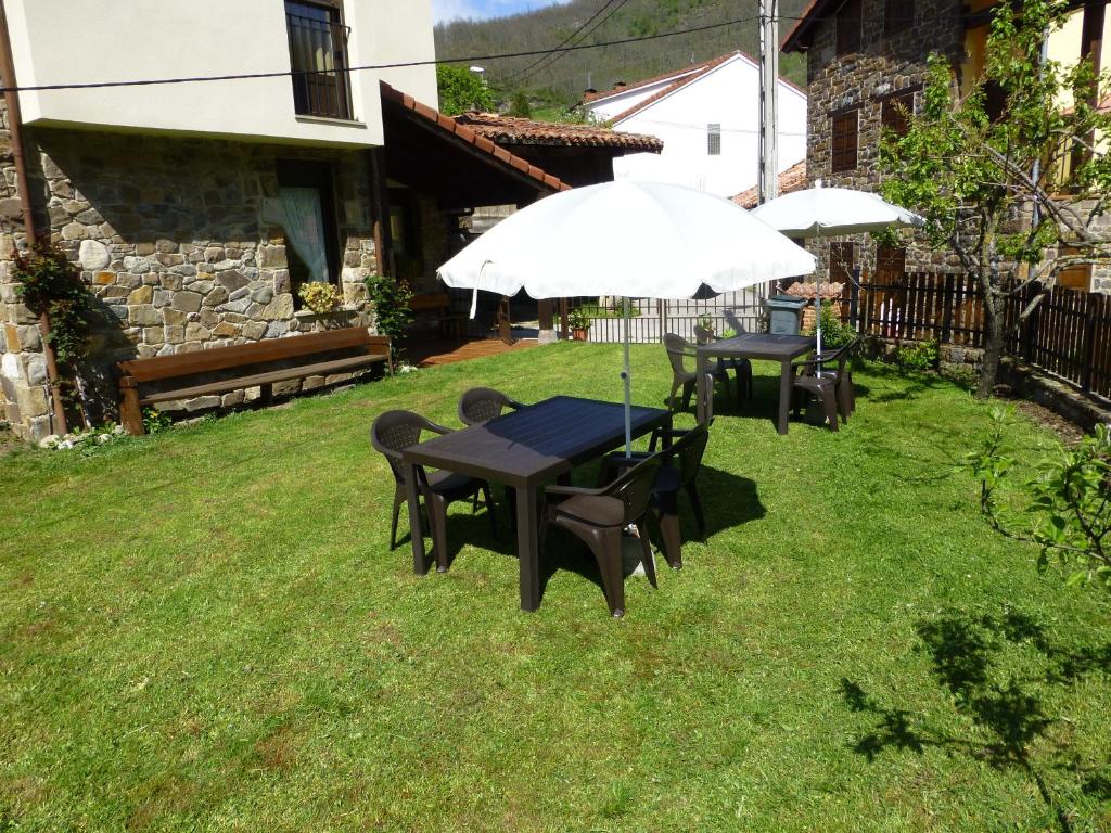 two tables and chairs with umbrellas in a yard at Albergue Turístico Briz in Espinama