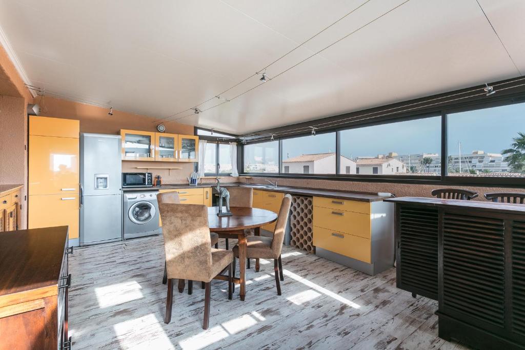 d'une cuisine avec une table, des chaises et des fenêtres. dans l'établissement Villa Naturiste Port Venus, au Cap d'Agde