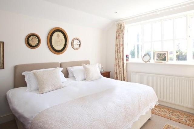 a white bedroom with a large white bed and a window at Hedingham Old Pottery in Castle Hedingham