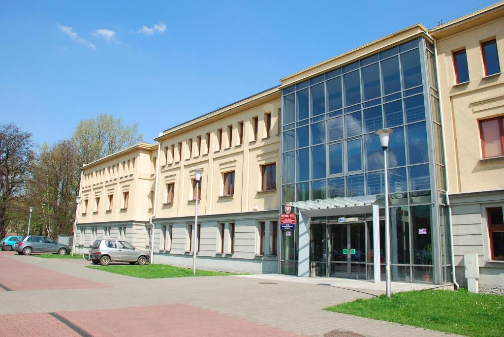 een groot glazen gebouw met auto's geparkeerd voor het bij Ośrodek Innowacja in Zabrze