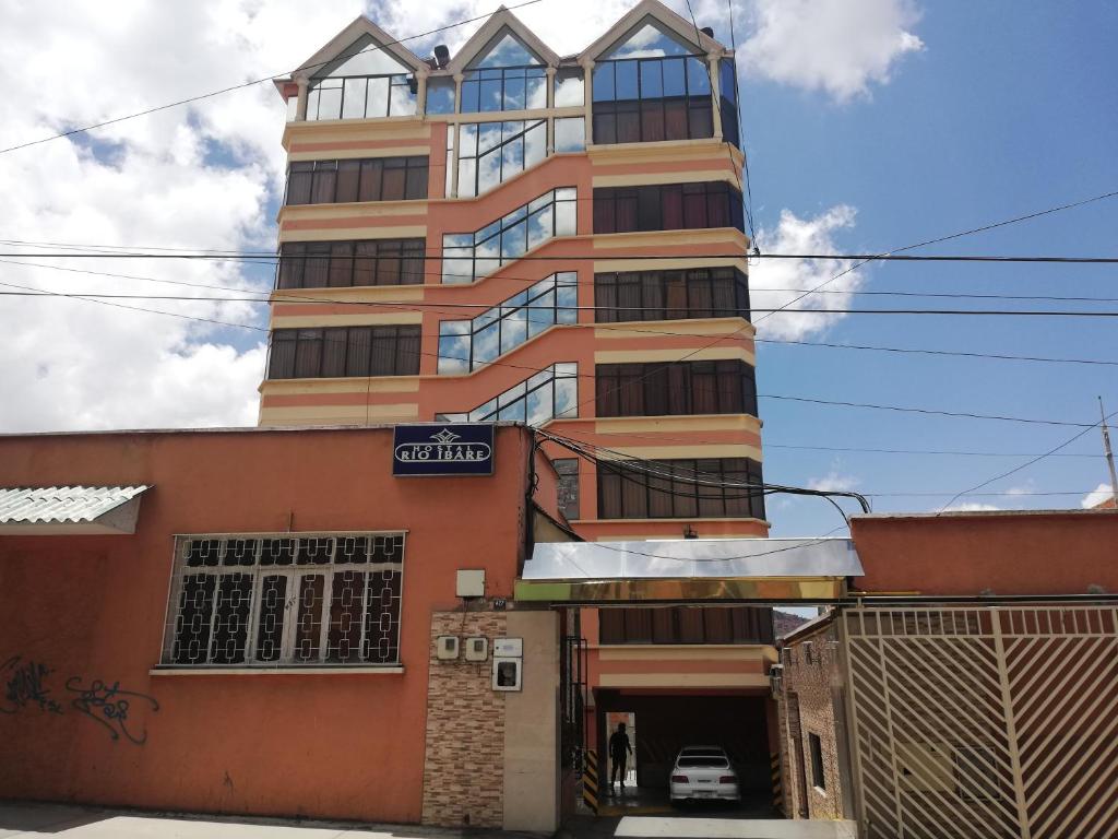 a tall building with a parking garage in front of it at Hostal Río ibare in La Paz