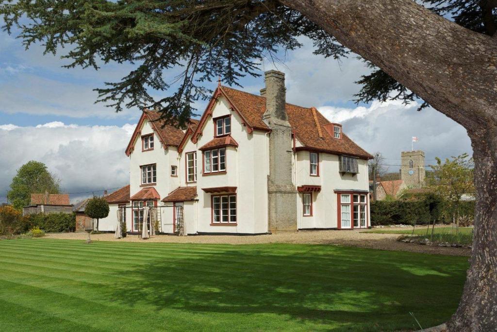 uma grande casa branca com um relvado verde em Haughley House em Stowmarket