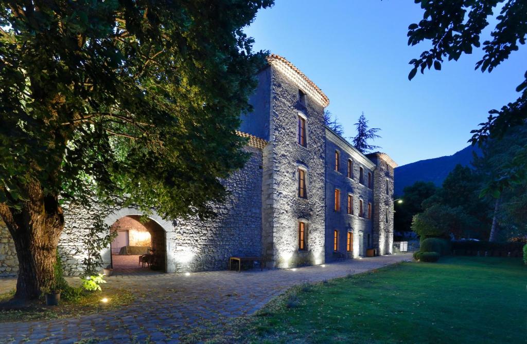 un gran edificio de piedra con un árbol delante de él en Chateau de Montfroc, en Montfroc