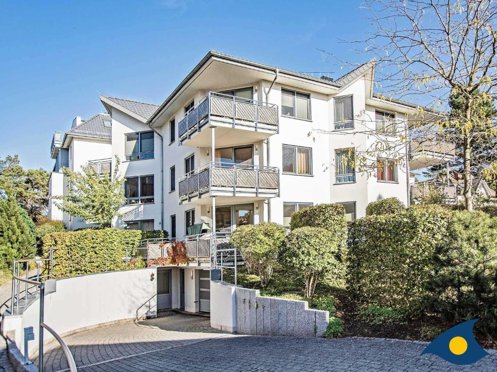 a white apartment building with bushes and trees at Haus Meeresrauschen Whg 03 in Bansin