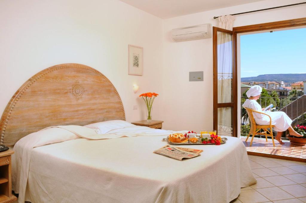 a bedroom with a bed with a plate of fruit on it at Hotel Angedras in Alghero