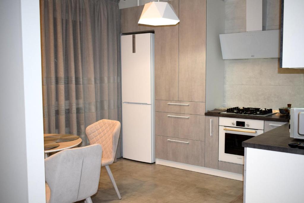 uma cozinha com um frigorífico branco e uma mesa em Apartment on Volodymyra Stelmakha 1b em Rivne