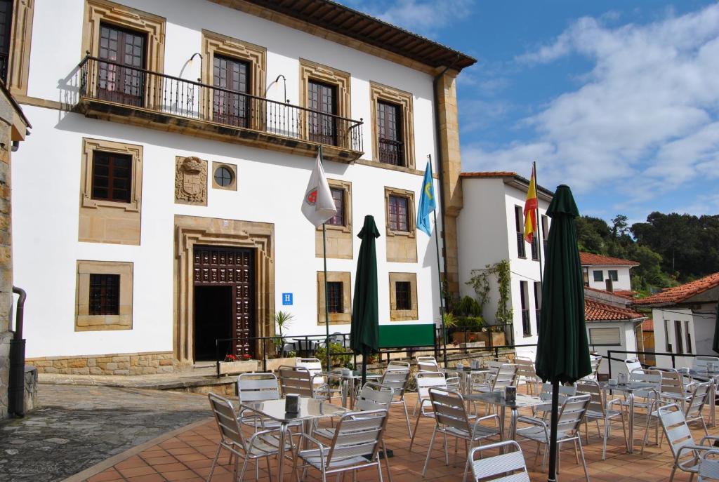 un grupo de mesas y sillas frente a un edificio en Hotel Palacio de los Vallados en Lastres