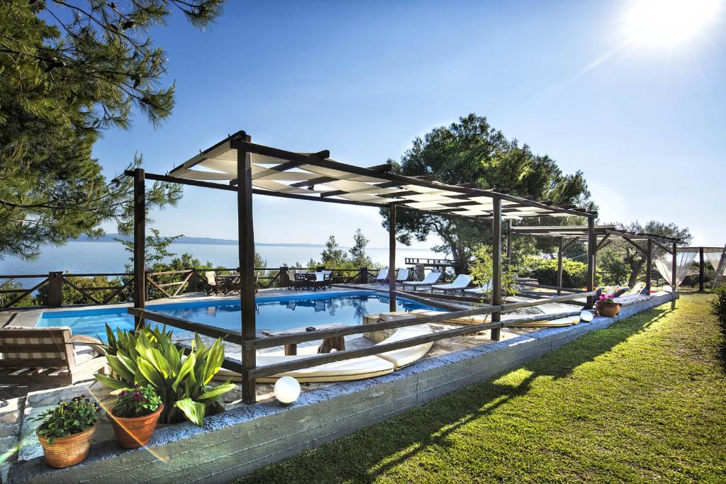 a swimming pool with a pavilion and a swimming poolvisor at Heos Accommodation in Ormos Panagias
