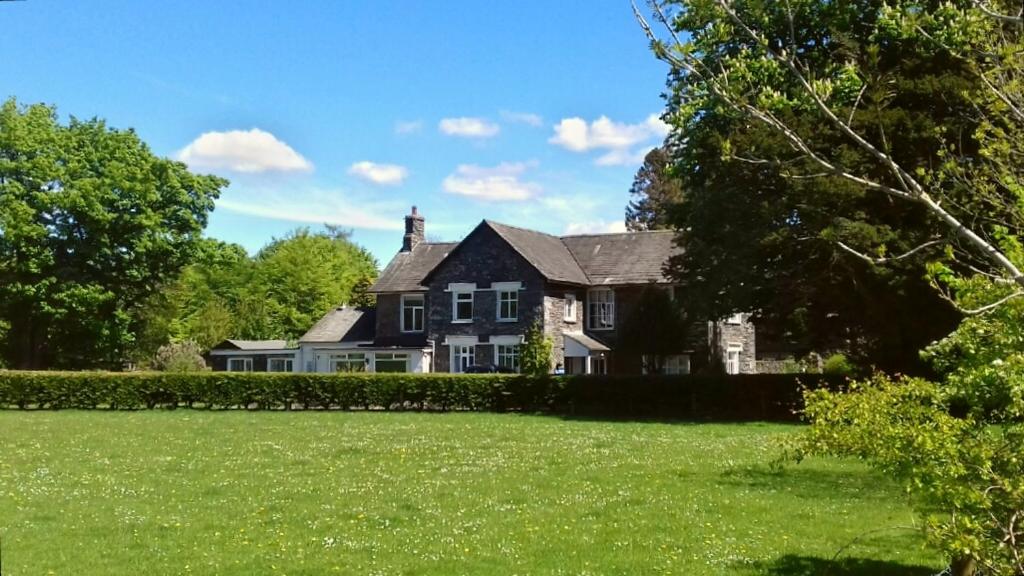 a black house with a green lawn in front of it at Bluebird Lodge in Coniston