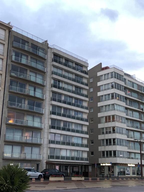 een groot gebouw met auto's geparkeerd voor het bij Appartement sur la digue in Knokke-Heist