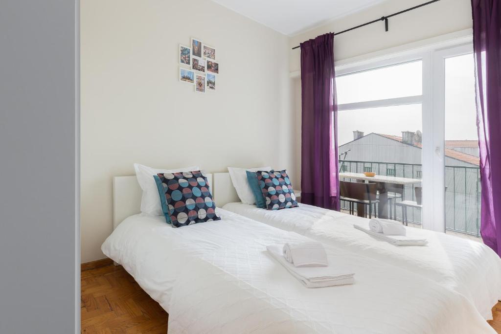 Un dormitorio blanco con una gran ventana con cortinas moradas en OPO Bolhao Flats by Destiny Houses, en Oporto
