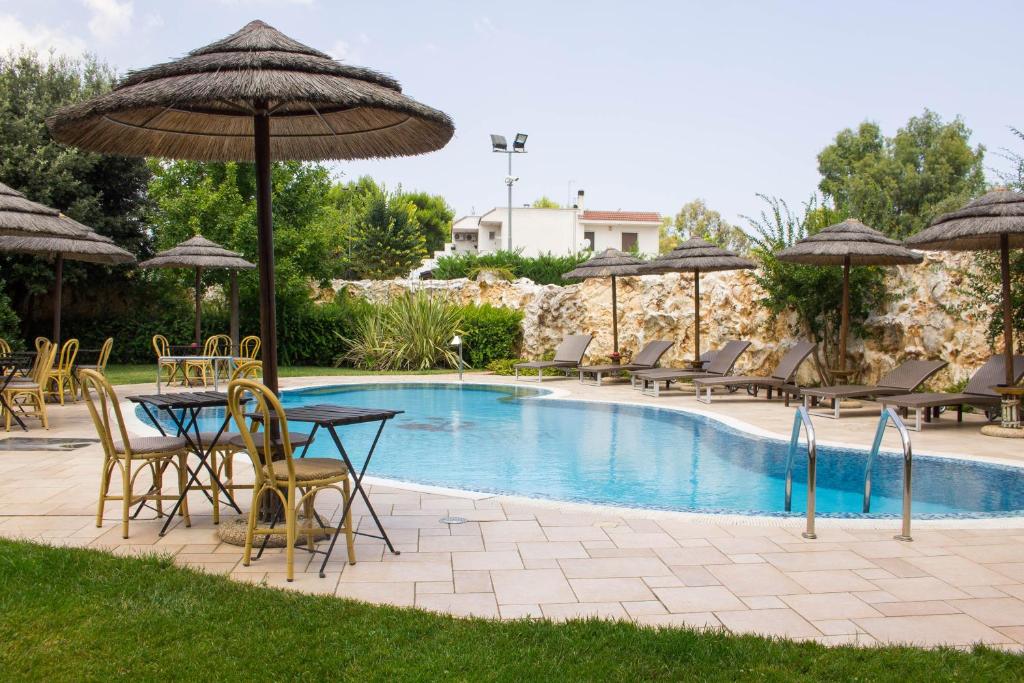 un patio con mesas, sillas y sombrillas junto a una piscina en Semiramide Palace Hotel, en Castellana Grotte