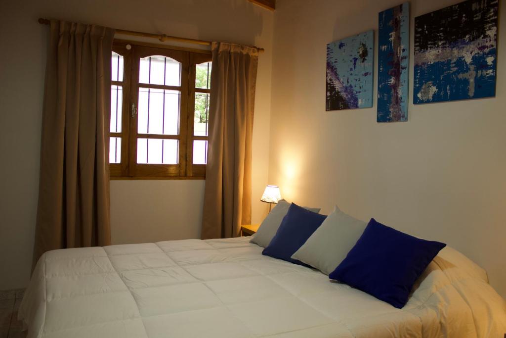 1 dormitorio con 1 cama blanca grande con almohadas azules en Apartamentos Irigoyen en San Rafael