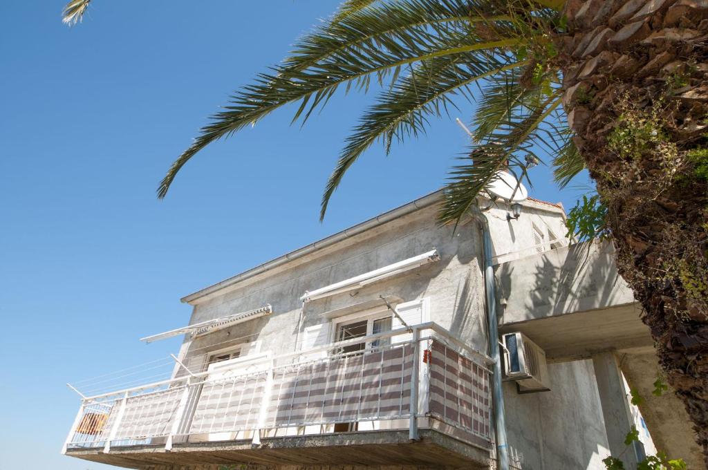 a white building with a balcony and a palm tree at Apartments Mira - great location in Splitska