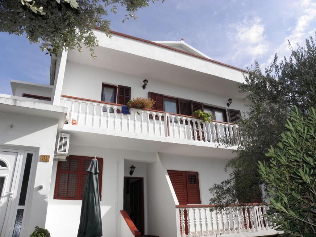 Casa blanca con persianas rojas y balcón en Apartments Pere - parking and barbecue, en Povljana