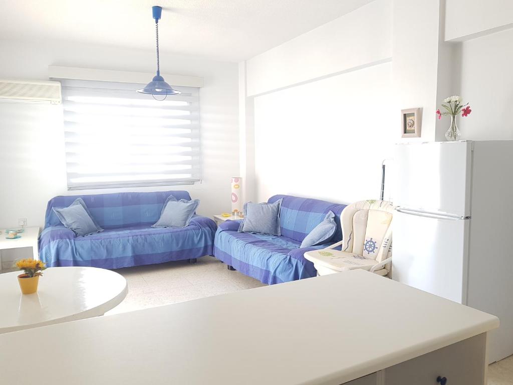 a living room with a blue couch and a white refrigerator at Cozy holyday apartament in Paralimni