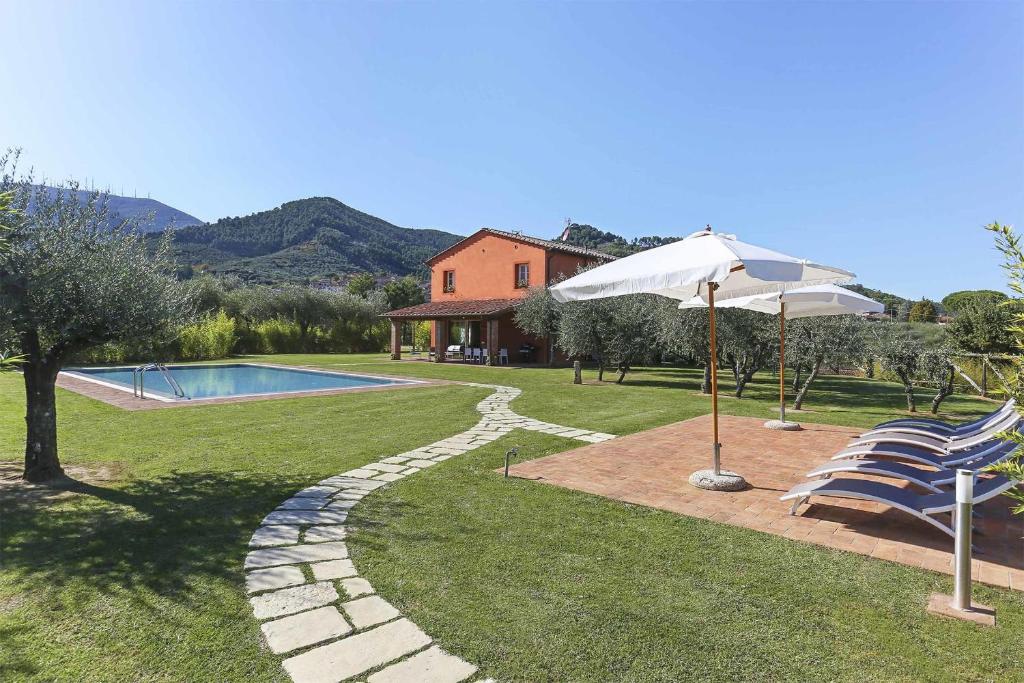 un patio con sombrilla, sillas y piscina en Il Grappolo, en Capannori