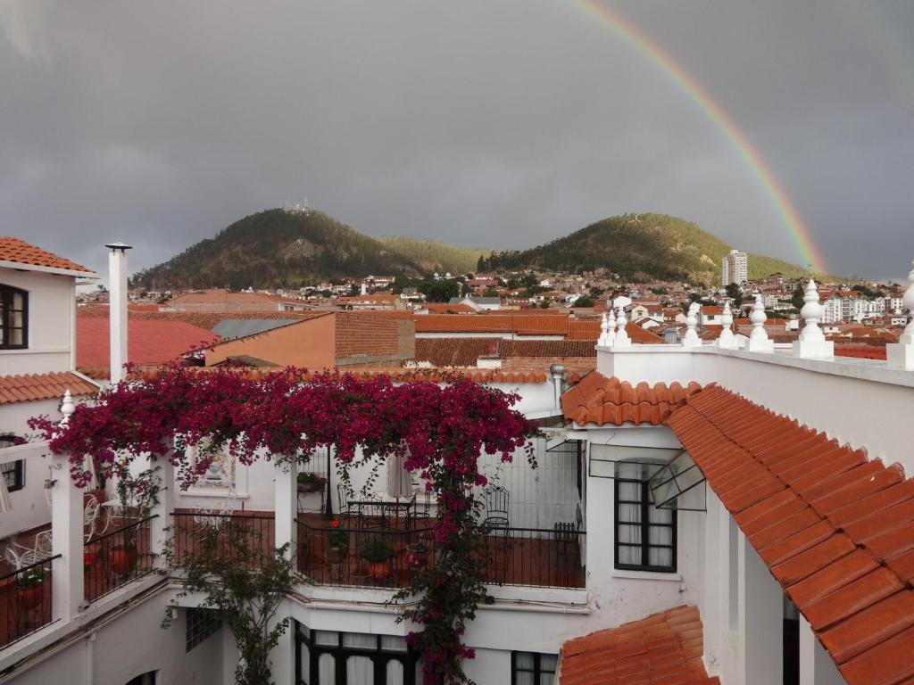 einen Regenbogen über einer Stadt mit lila Blumen in der Unterkunft El Hotel de Su Merced in Sucre