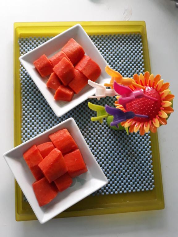 two plates of watermelon and a flower on a tray at Green Teak House in Bangkok
