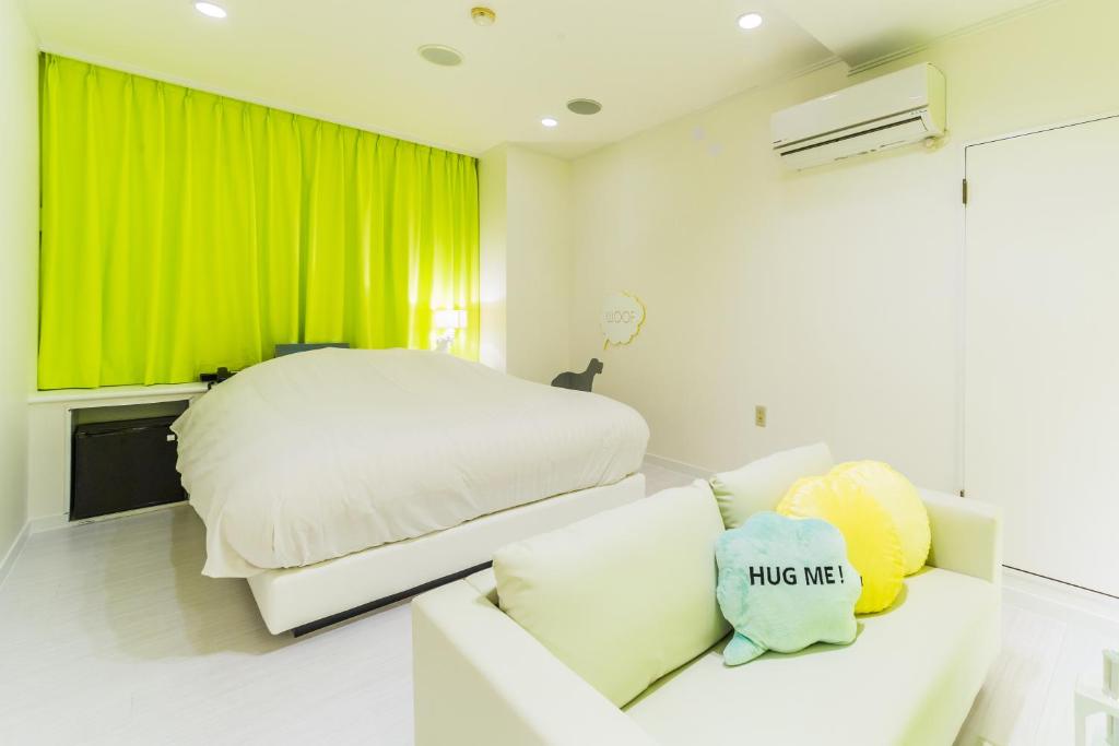 a bedroom with a white bed and a couch at Hotel Aqua Color (Adult only) in Fukushima