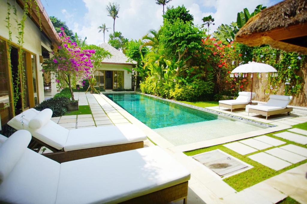 a backyard with a swimming pool and a villa at Villa Bali Asri Batubelig in Seminyak