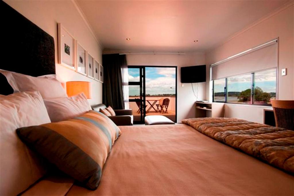a large bedroom with a large bed with a balcony at Marineland Motel in Napier