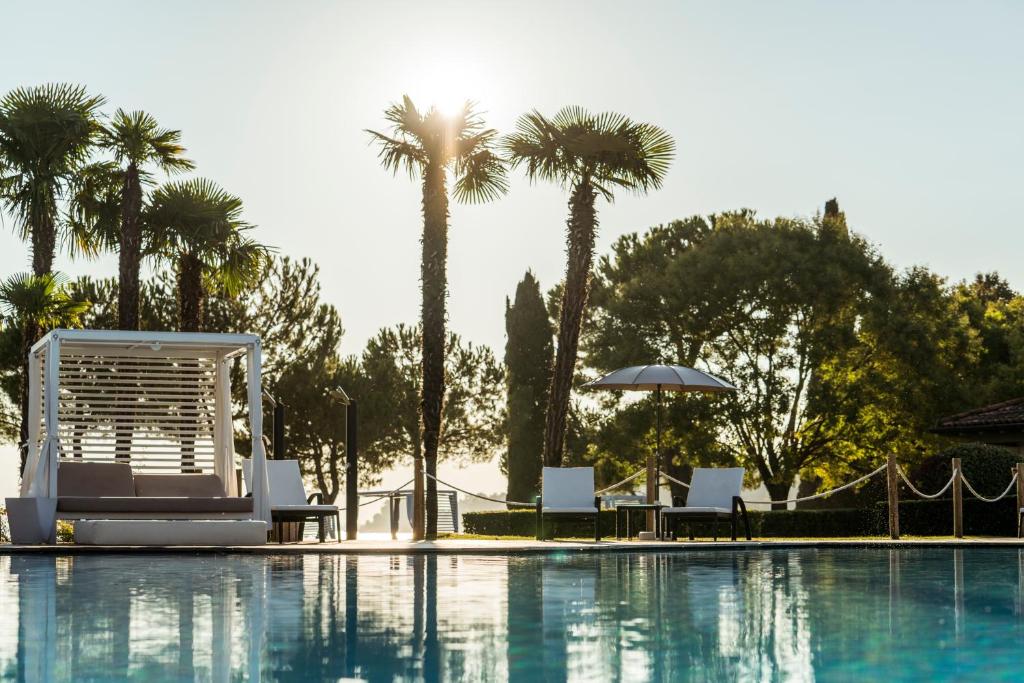 einen Pool mit Stühlen und Palmen in der Unterkunft Splendido Bay Luxury Spa Resort in Padenghe sul Garda