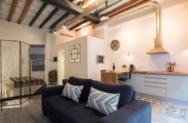 a living room with a couch and a kitchen at Beautiful loft in old town in Alicante
