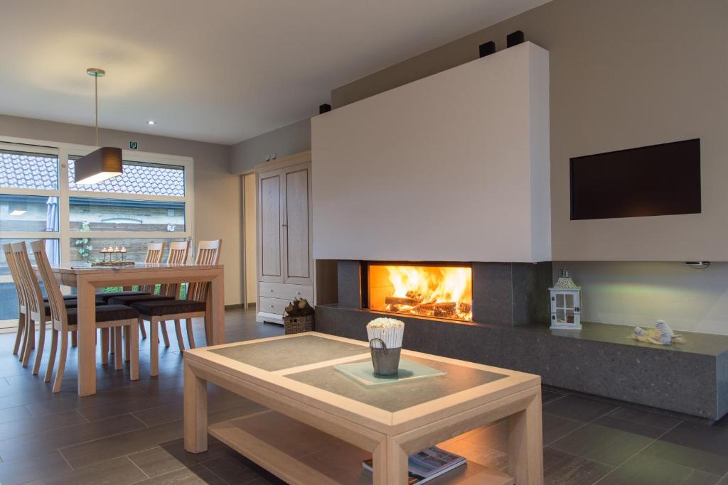 a living room with a fireplace and a table at VILLA WESTHOEK in Poelkapelle