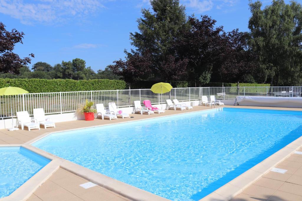 a swimming pool with chairs and umbrellas next to it at Village Vacances de Chantonnay in Chantonnay